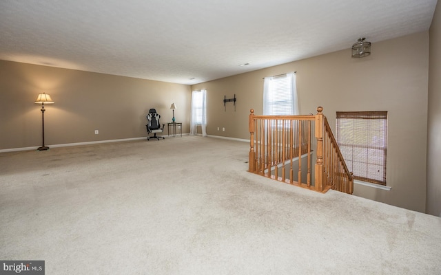 spare room featuring baseboards, a textured ceiling, and carpet flooring