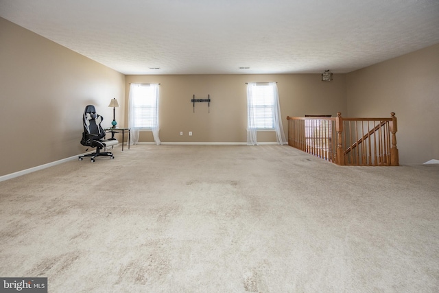 interior space featuring a wealth of natural light, carpet, a textured ceiling, and an upstairs landing