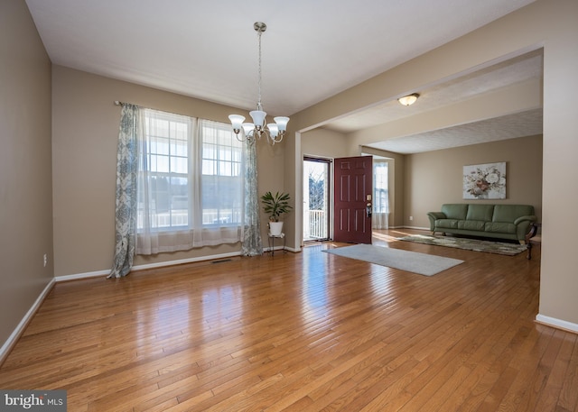 foyer featuring baseboards, plenty of natural light, a chandelier, and light wood-style floors