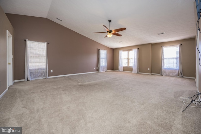 spare room with vaulted ceiling, visible vents, ceiling fan, and light carpet