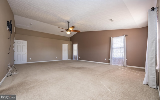 empty room featuring carpet floors, visible vents, vaulted ceiling, and a textured ceiling