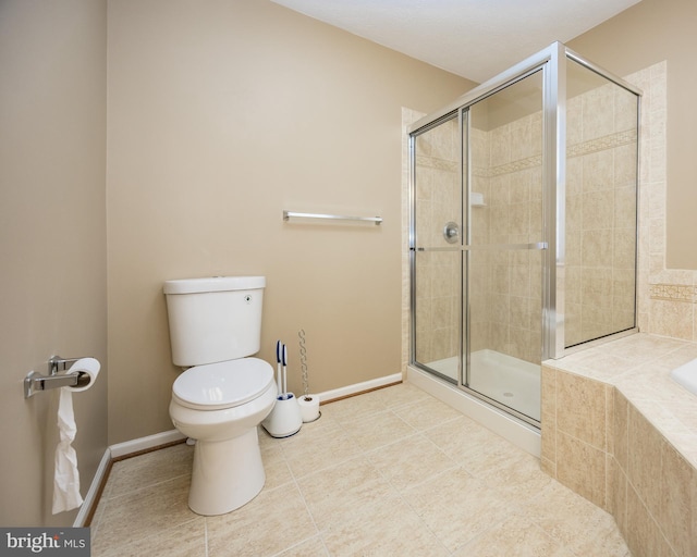 bathroom featuring toilet, a shower stall, baseboards, and a relaxing tiled tub