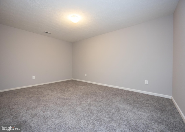 spare room with carpet, baseboards, visible vents, and a textured ceiling