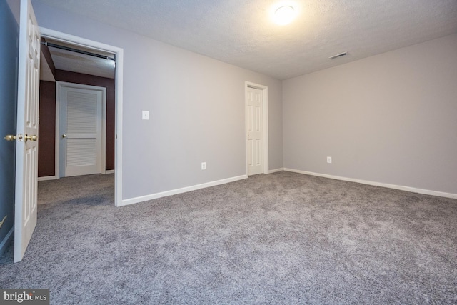 empty room featuring a textured ceiling, carpet floors, visible vents, and baseboards