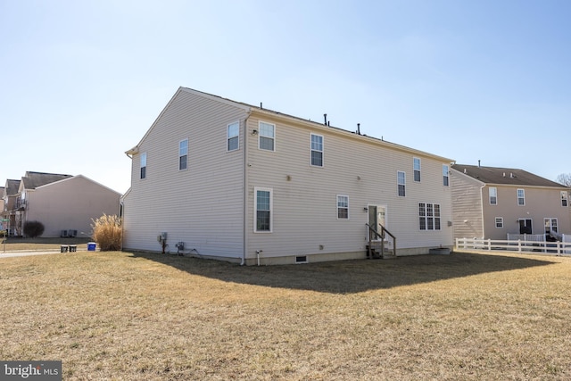 rear view of property with entry steps, fence, and a yard