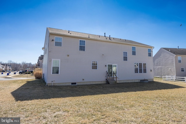 back of house featuring entry steps, a lawn, and fence