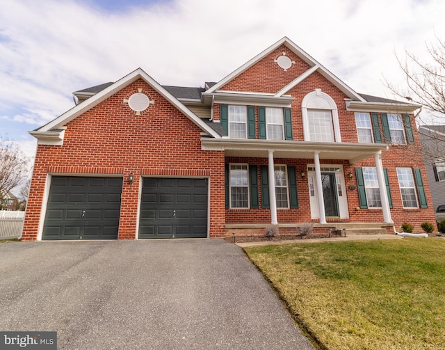 view of front of house with covered porch, a front yard, aphalt driveway, and brick siding