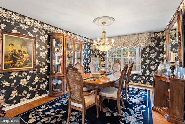 dining room featuring baseboards, an inviting chandelier, wood finished floors, and wallpapered walls