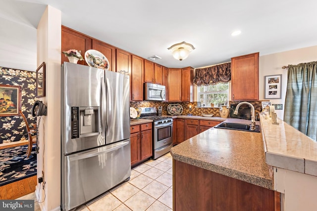 kitchen featuring stainless steel appliances, visible vents, backsplash, a sink, and a peninsula