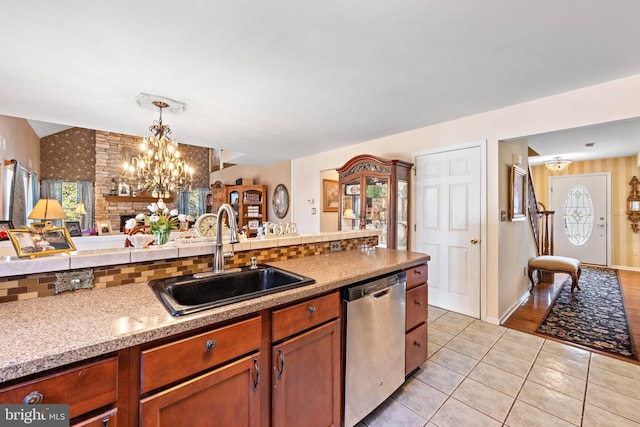 kitchen featuring light tile patterned floors, a sink, open floor plan, hanging light fixtures, and dishwasher