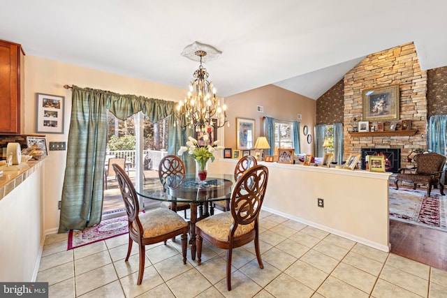 dining area featuring light tile patterned floors, lofted ceiling, a stone fireplace, a chandelier, and baseboards