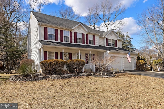 traditional-style home featuring a garage, a porch, and aphalt driveway