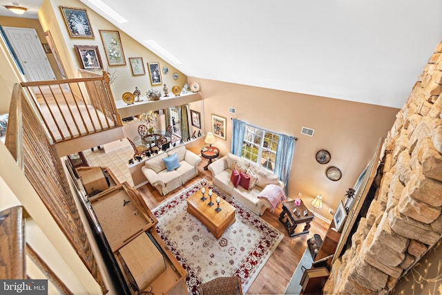 living area featuring vaulted ceiling, stairway, wood finished floors, and visible vents