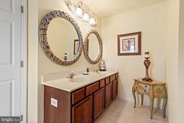 bathroom with baseboards, double vanity, a sink, and tile patterned floors