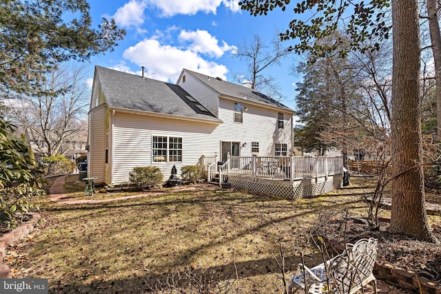 rear view of property featuring a shingled roof, a lawn, and a wooden deck