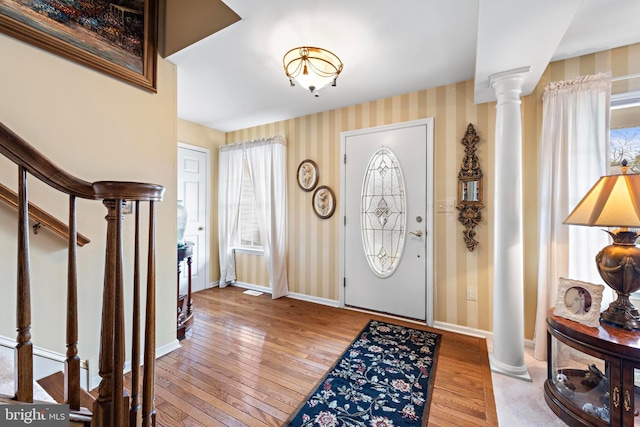 entrance foyer featuring hardwood / wood-style flooring, baseboards, stairway, decorative columns, and wallpapered walls