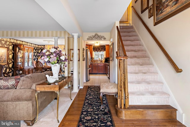 entryway with baseboards, stairway, ornate columns, and wallpapered walls