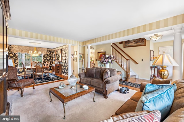 living room with a chandelier, stairway, decorative columns, and wallpapered walls