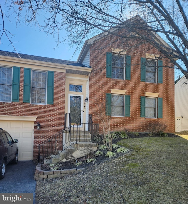 view of front of house with brick siding, an attached garage, and driveway