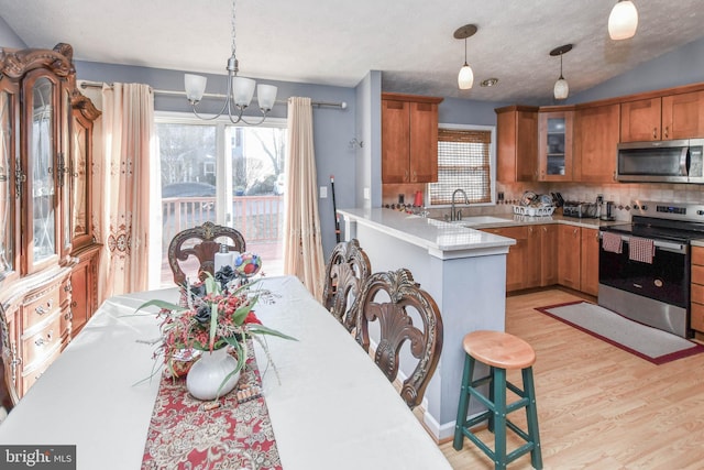 kitchen with a sink, light countertops, brown cabinets, and stainless steel appliances