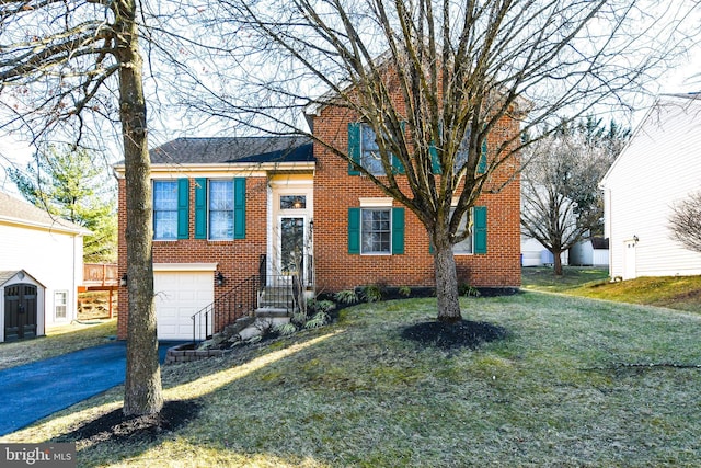 tri-level home featuring brick siding, an attached garage, aphalt driveway, and a front lawn