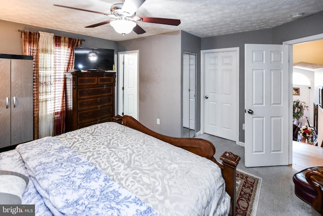 bedroom with a ceiling fan, multiple closets, and a textured ceiling