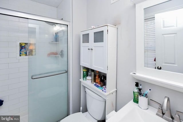 bathroom featuring toilet, a stall shower, and a sink