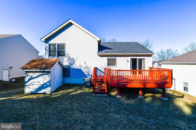 back of house with a shingled roof, a deck, a yard, an outbuilding, and a storage unit