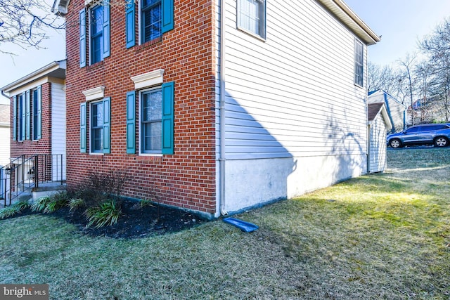 view of home's exterior with brick siding and a lawn