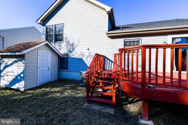 rear view of property featuring a deck, an outdoor structure, a storage unit, and a yard