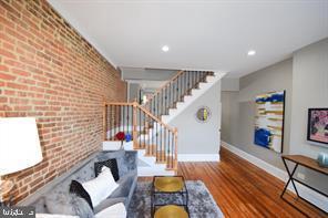 living area featuring recessed lighting, stairway, brick wall, wood finished floors, and baseboards