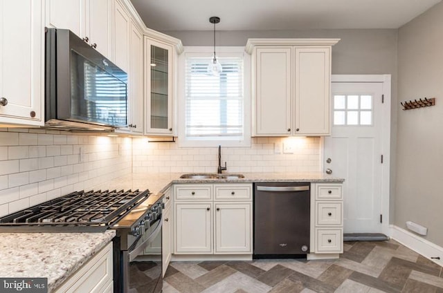 kitchen with pendant lighting, a sink, black appliances, light stone countertops, and baseboards