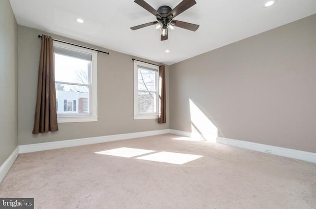 spare room featuring recessed lighting, light colored carpet, and baseboards