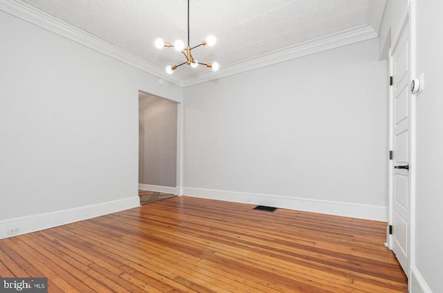 unfurnished room featuring light wood finished floors, a notable chandelier, baseboards, and crown molding