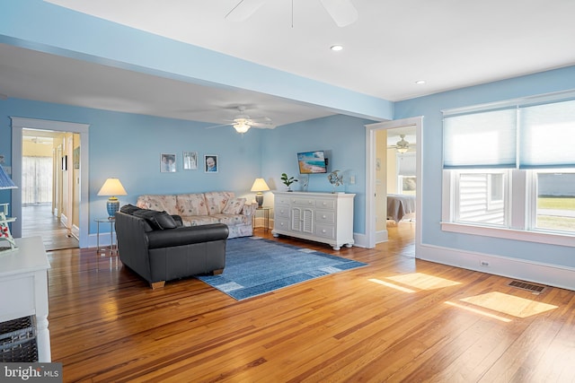 living area with a healthy amount of sunlight, visible vents, wood-type flooring, and baseboards