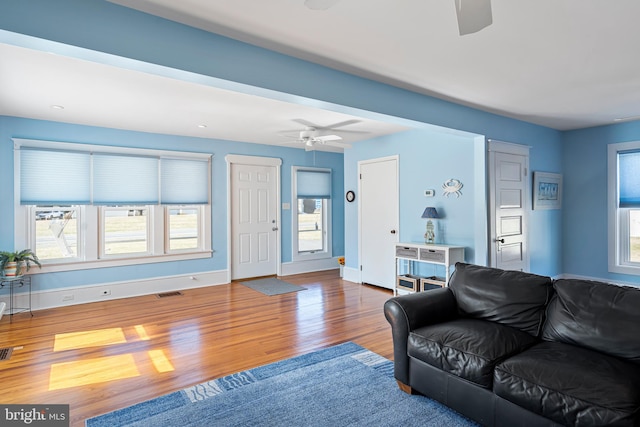 living area featuring visible vents, baseboards, a healthy amount of sunlight, and wood finished floors