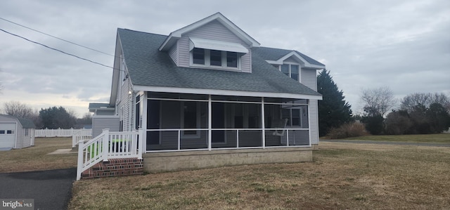 back of house featuring a lawn, a shingled roof, and a sunroom