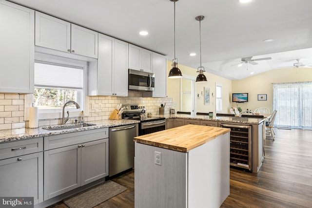 kitchen featuring wooden counters, a peninsula, a sink, stainless steel appliances, and wine cooler