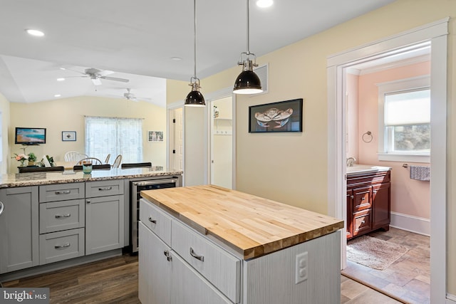 kitchen with wine cooler, gray cabinetry, a center island, and butcher block counters