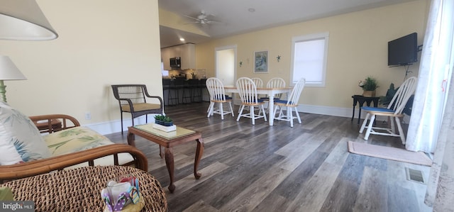 living room featuring visible vents, baseboards, ceiling fan, and dark wood-style flooring