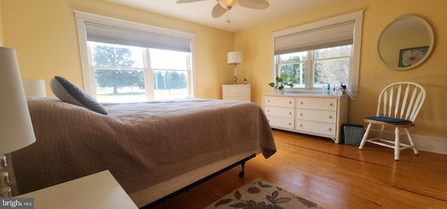 bedroom featuring light wood finished floors, multiple windows, and a ceiling fan