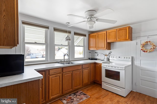 kitchen featuring a sink, light wood-style floors, brown cabinetry, and electric stove