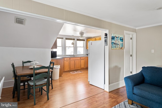 dining area featuring a ceiling fan, crown molding, light wood-style floors, and visible vents