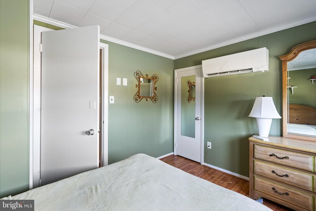 bedroom with ornamental molding, a wall unit AC, and wood finished floors