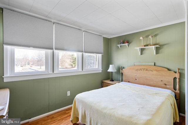 bedroom featuring ornamental molding, baseboards, and wood finished floors