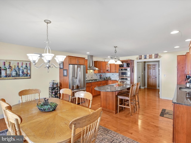 dining space with a chandelier, recessed lighting, light wood-style flooring, and baseboards