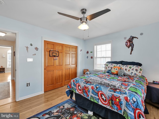 bedroom featuring ceiling fan, a closet, baseboards, and wood finished floors