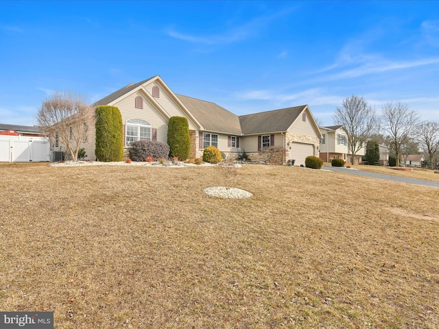 view of front of property with a garage, fence, stone siding, a gate, and a front yard