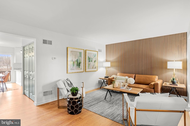 living area featuring light wood finished floors, visible vents, and baseboards