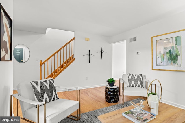 living area with stairway, baseboards, visible vents, and wood finished floors